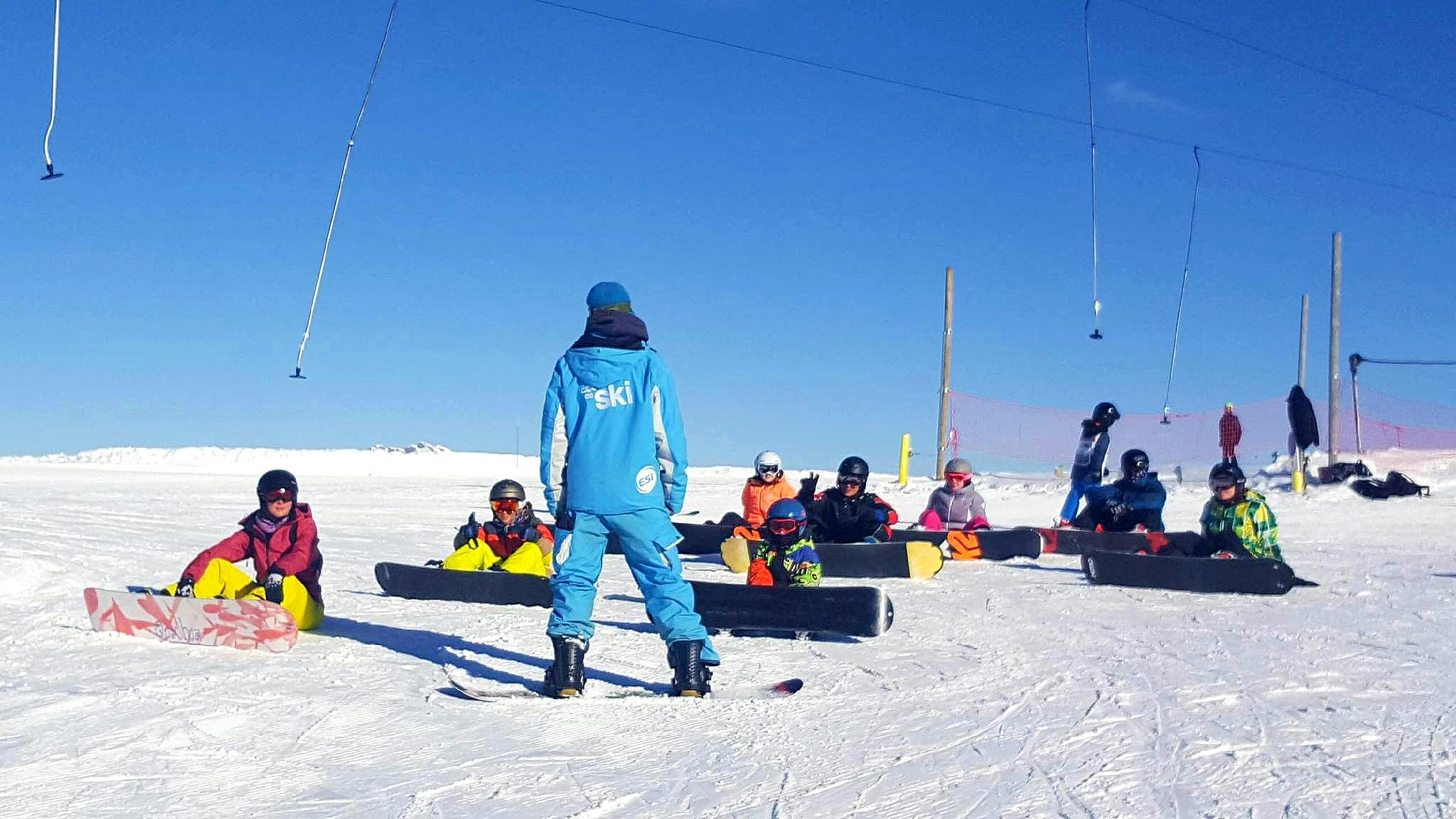 Students are listening attentively to their instructor during their Snowboarding Lessons for Kids & Adults of All Levels with ESI Grand Massif.
