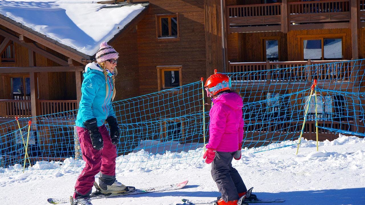 Una joven esquiadora está aprendiendo a esquiar con el apoyo de su instructor de esquí de la escuela Snocool en Tignes, durante sus clases particulares de esquí para niños de todas las edades.